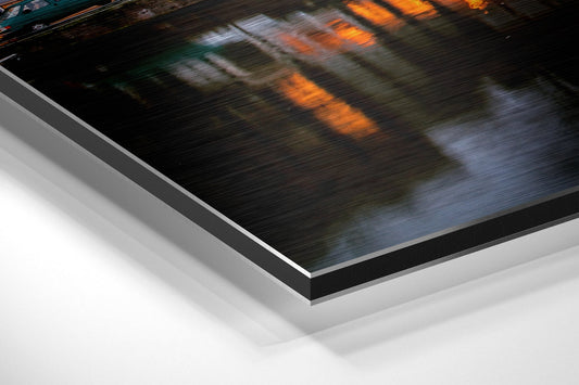 Canal houses and arched bridge at dusk brushed aluminum panel corner close-up showing the brushed metal grain