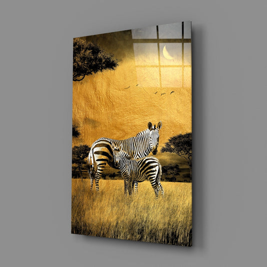 Zebra mother and foal under a gold sky glass wall art hanging on a plain gray wall