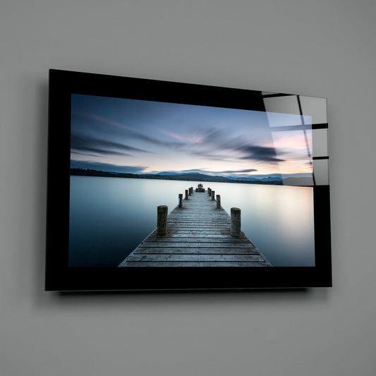 Blue twilight lake jetty glass wall art shown at an angle against a gray wall
