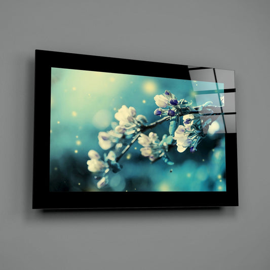 White blossom branch on teal glass wall art with a wide black border on a gray wall