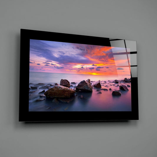 Rocky shore violet sunset glass wall art shown at an angle against a gray wall