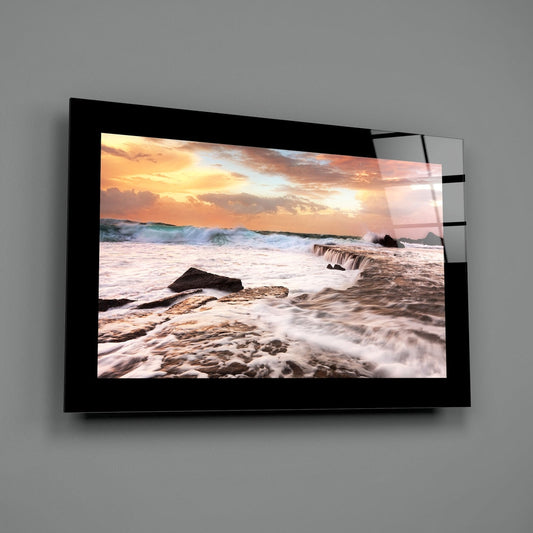 Cloudy sunset waves glass wall art shown at an angle against a gray wall