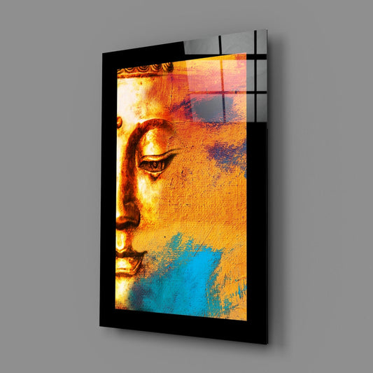 Golden Buddha face glass wall art on a gray wall, angled to show the glossy front