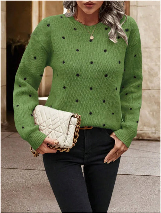 deep dark-green knit pullover featuring small black dots, paired with black jeans and a white quilted handbag