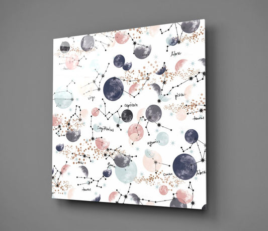 Zodiac constellations and pastel moons glass wall art at an angle against a gray background