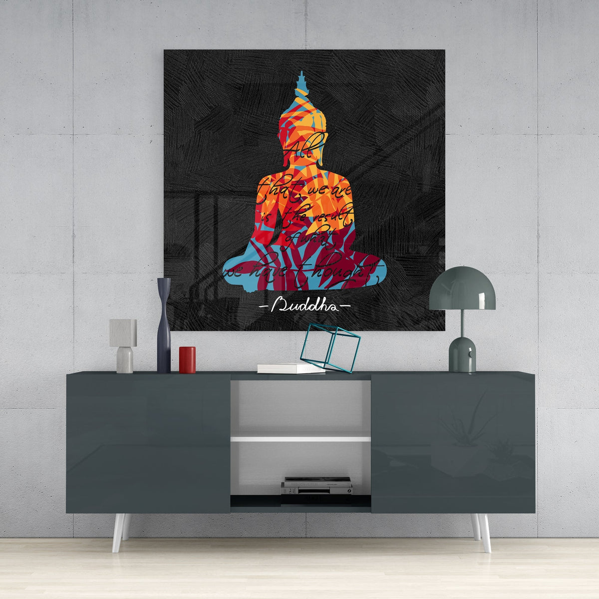 Buddha quote on black square glass wall art on a concrete wall above a dark gray sideboard