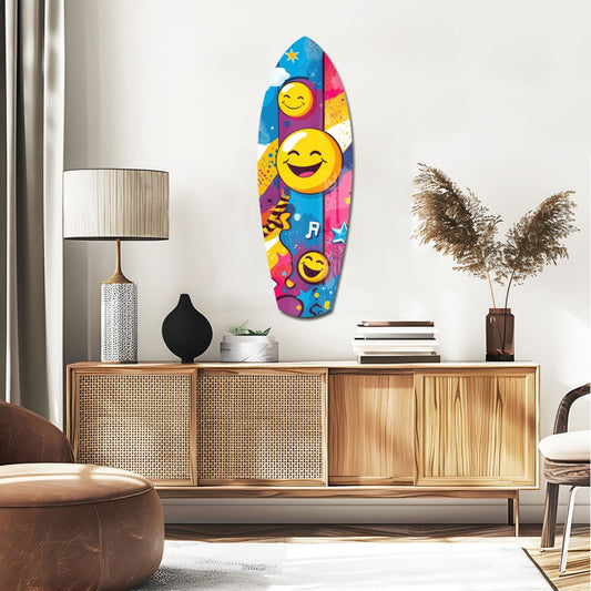 Laughing faces surfboard glass wall art above a rattan sideboard with a table lamp and pampas grass