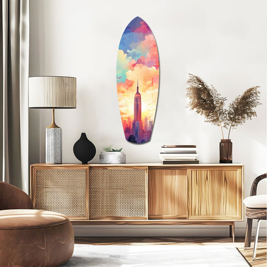 New York pastel skyline surfboard glass wall art above a rattan sideboard with a lamp and pampas grass