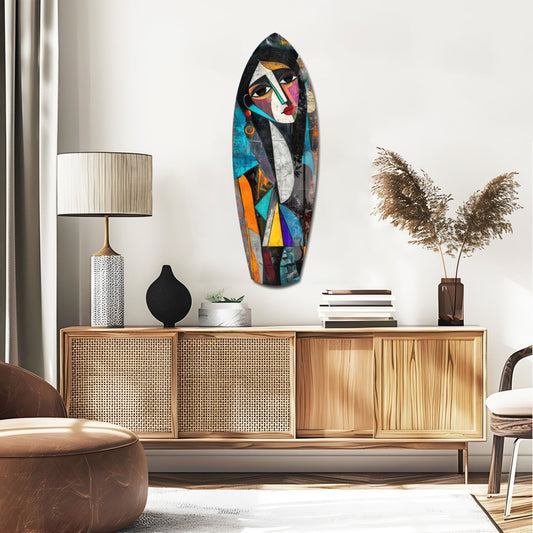 Cubist woman portrait surfboard glass wall art above a rattan sideboard with a table lamp and pampas grass