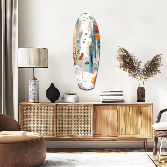 Woman by a coral sea surfboard glass wall art above a rattan sideboard with a table lamp and pampas grass