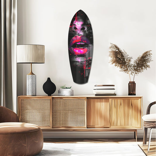 Hot pink lips with red splatter surfboard glass wall art above a rattan sideboard with a table lamp and pampas grass