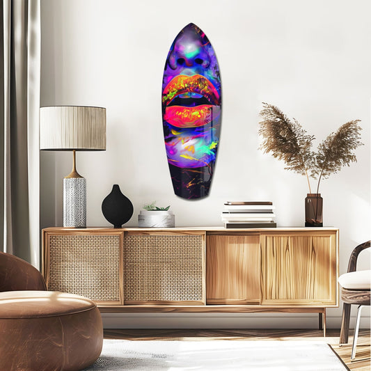 Orange lips with purple swirls surfboard glass wall art above a rattan sideboard with a table lamp and pampas grass