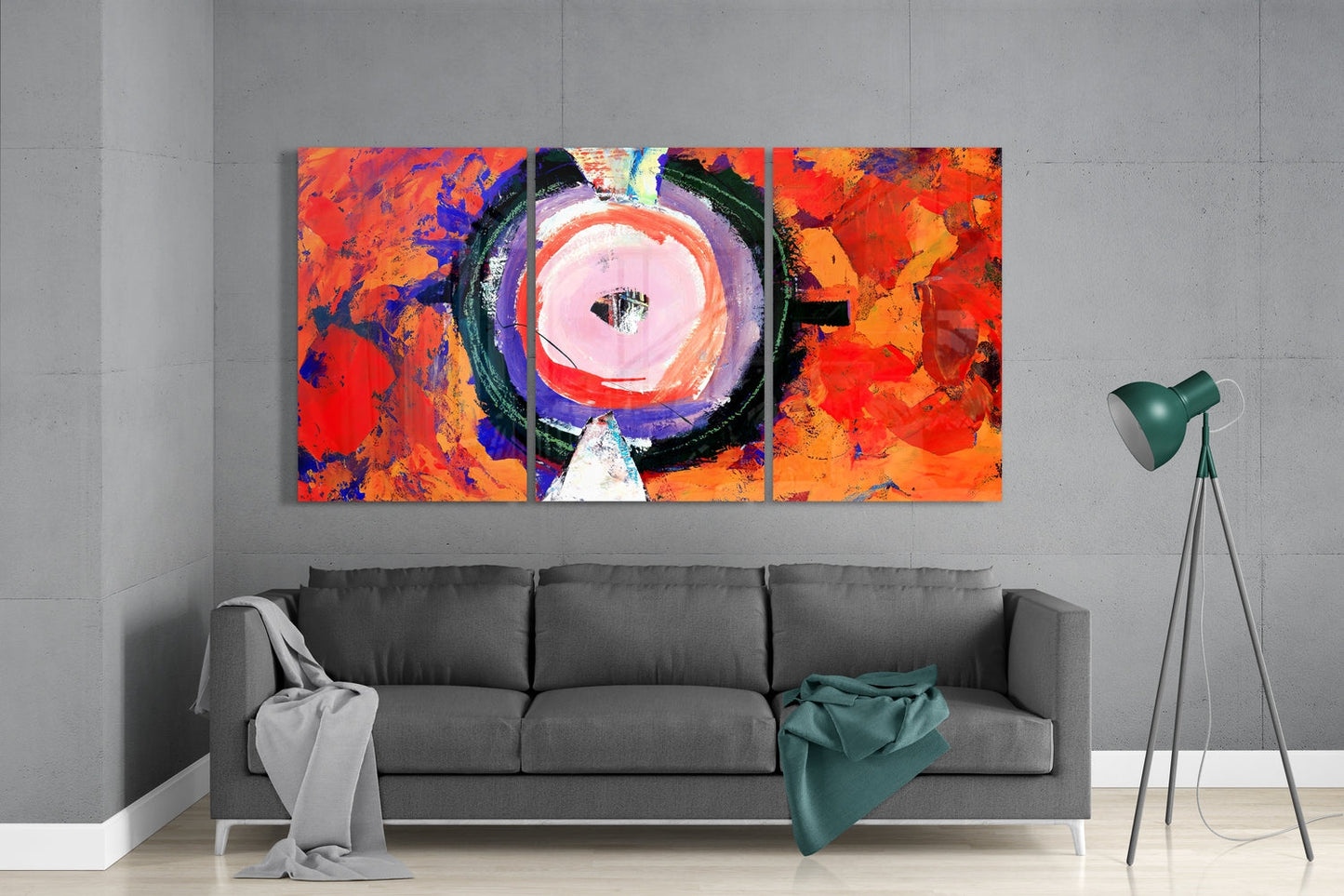 Pink circle on red and orange abstract glass wall art set above a gray sofa beside a tripod floor lamp