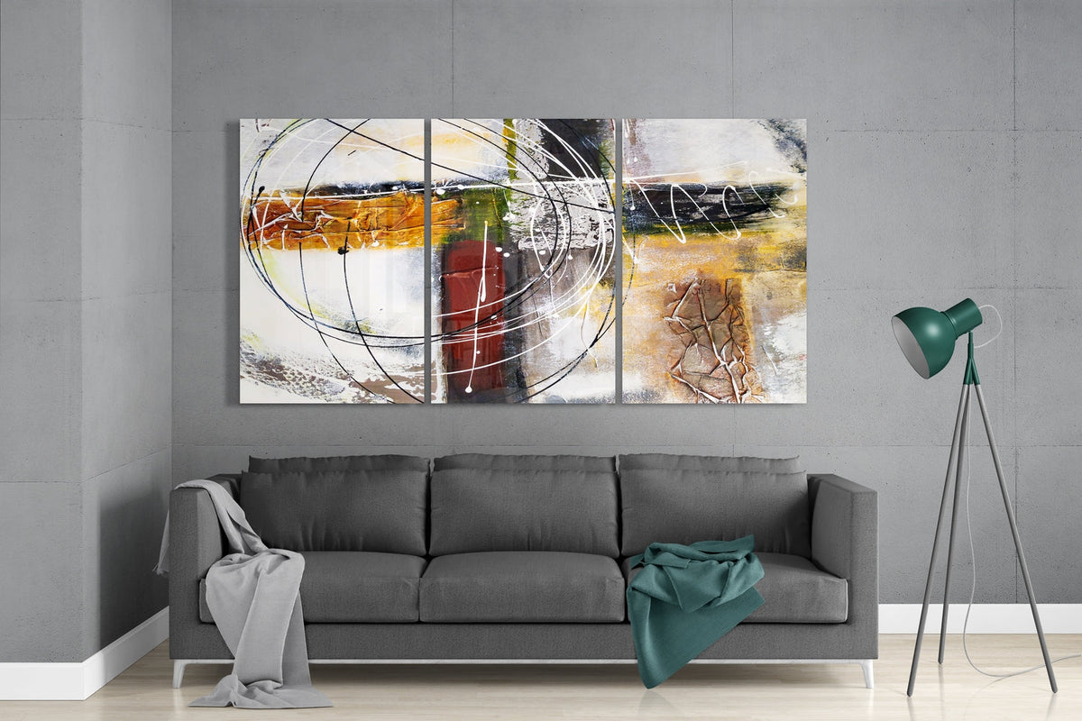 Rust and cream abstract circles glass wall art set above a gray sofa beside a tripod floor lamp