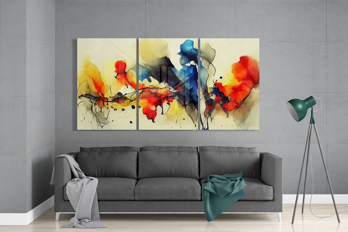 Red, yellow and blue ink splash glass wall art set above a gray sofa beside a tripod floor lamp