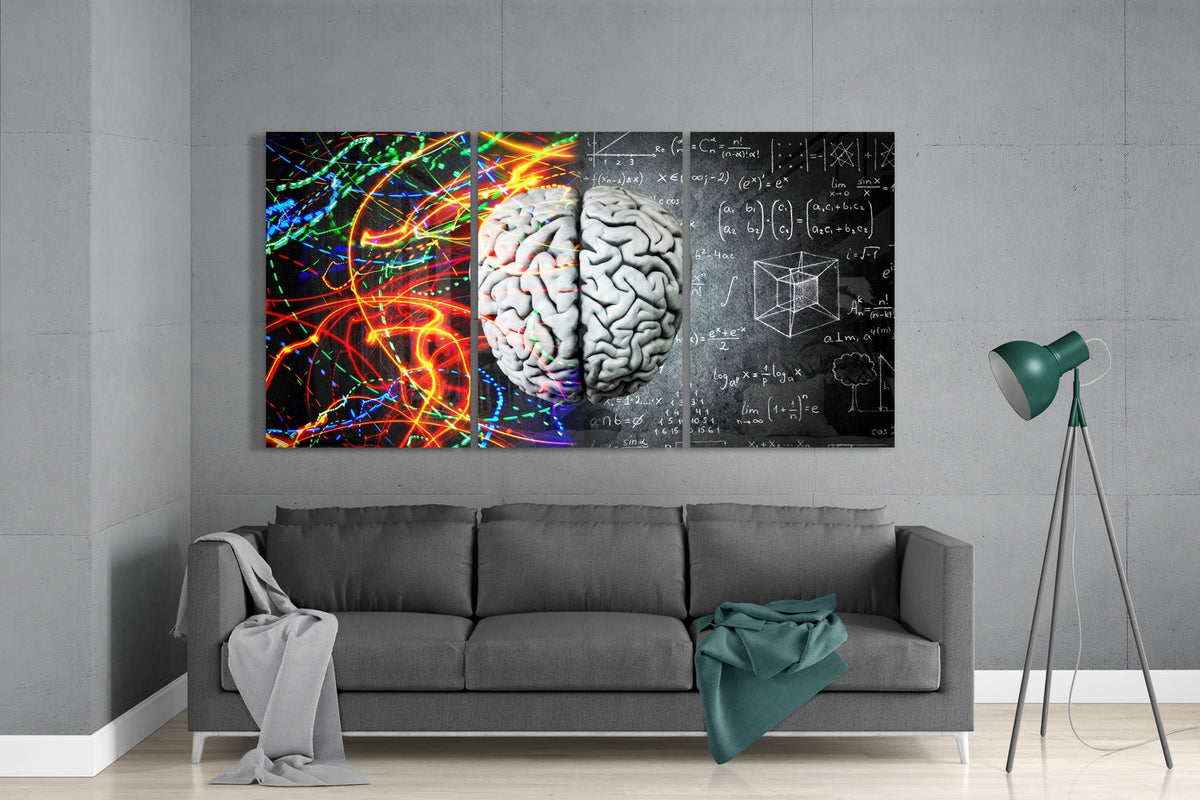 Brain with light trails and math formulas 3-panel glass wall art set above a gray sofa beside a tripod floor lamp