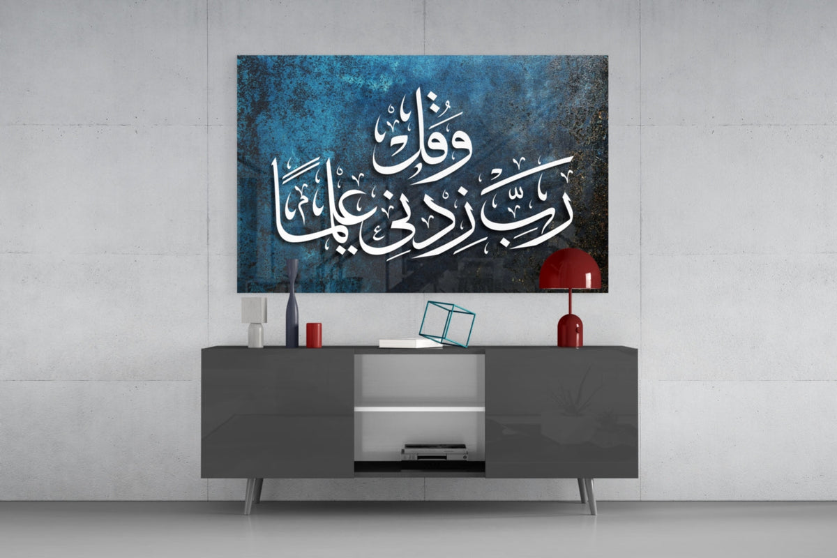 Teal Rabbi Zidni Ilma calligraphy glass wall art above a gray sideboard with a red table lamp