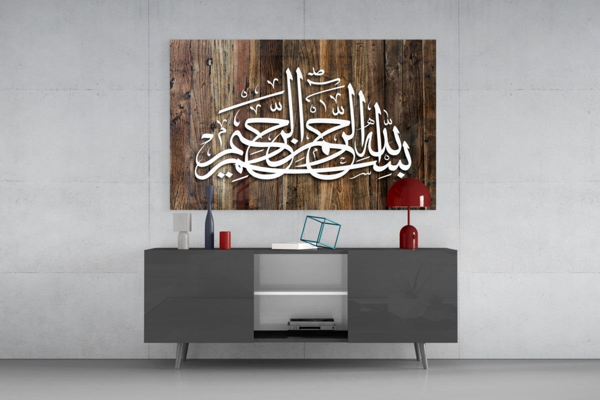 Wood grain Bismillah calligraphy glass wall art above a gray sideboard with a red table lamp