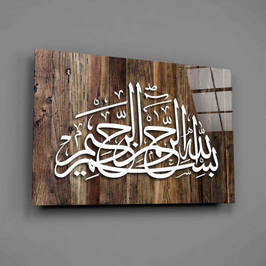 Wood grain Bismillah calligraphy glass wall art hanging on a plain gray wall, seen at an angle