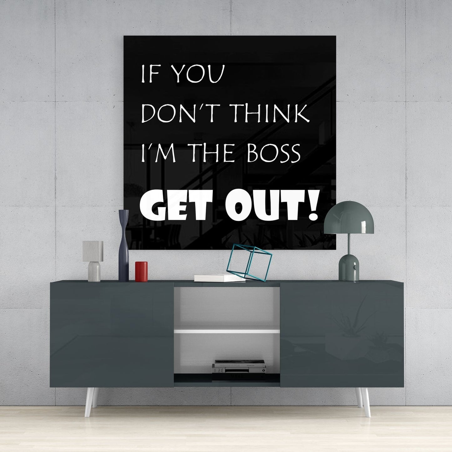 Black and white boss quote glass wall art above a dark gray sideboard on a concrete wall beside a dome lamp