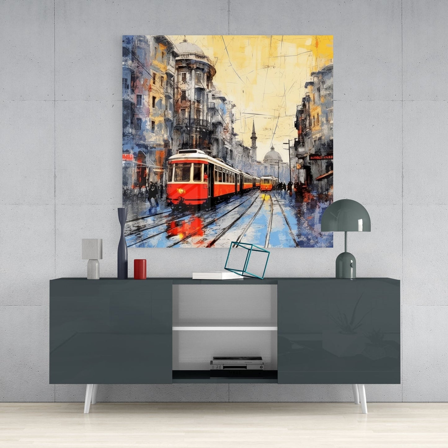 Red tram under an amber sky glass wall art above a gray sideboard with a small lamp