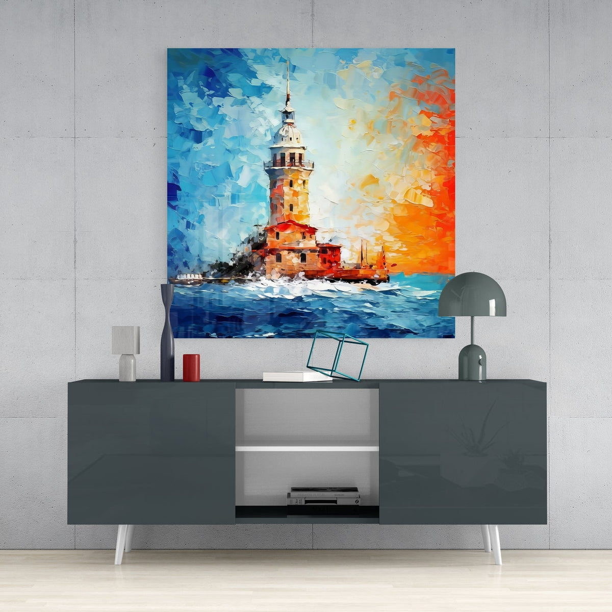 Blue and orange sea tower glass wall art above a dark gray sideboard with a dome lamp and vase