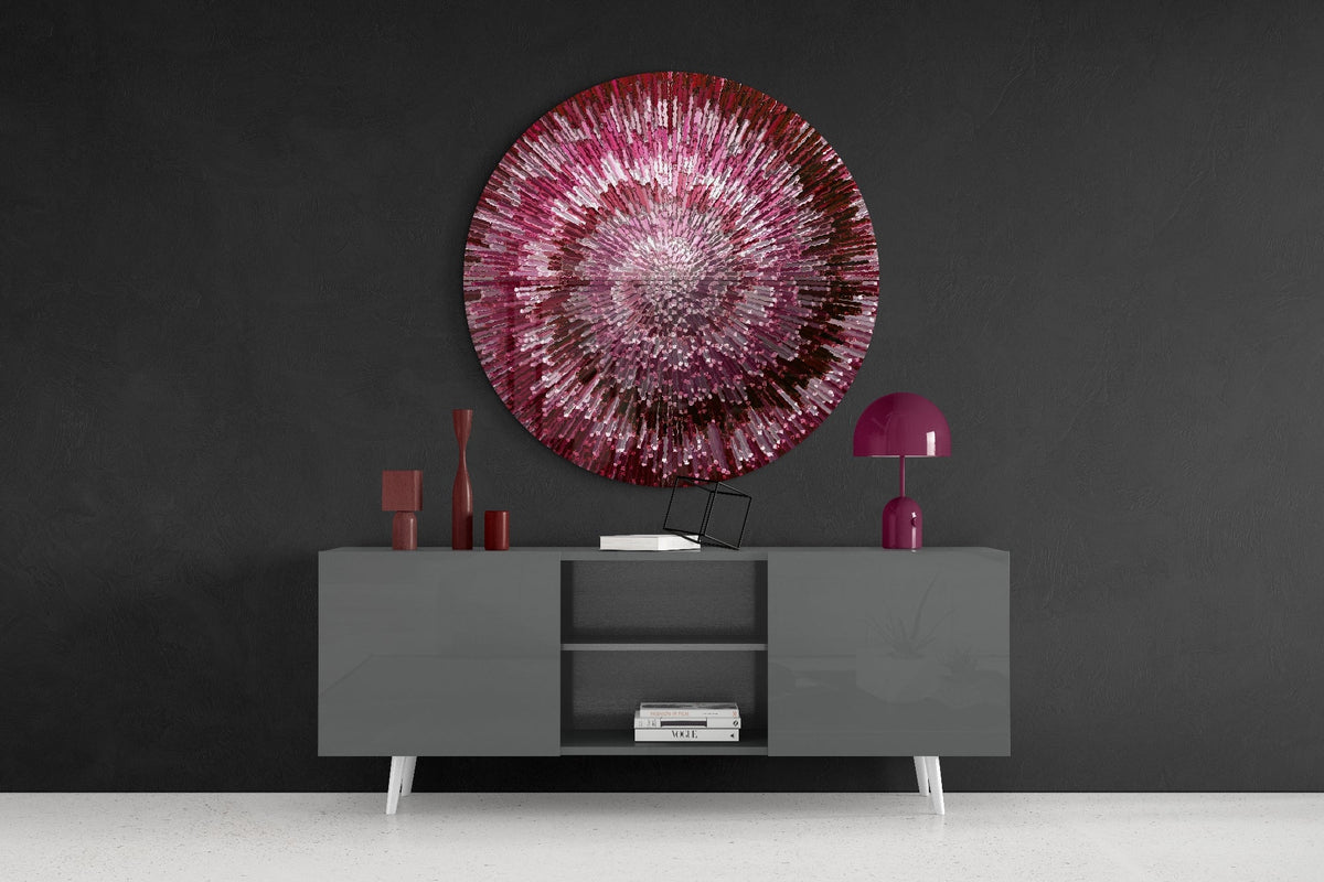 Ruby helix burst round glass wall art on a dark wall above a gray sideboard with vases