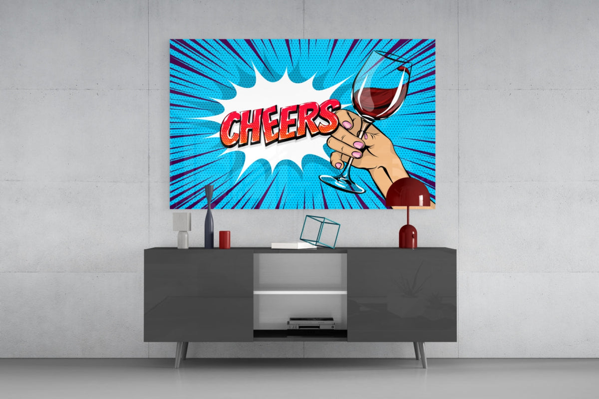 Pop art cheers glass wall art above a gray sideboard with a red table lamp