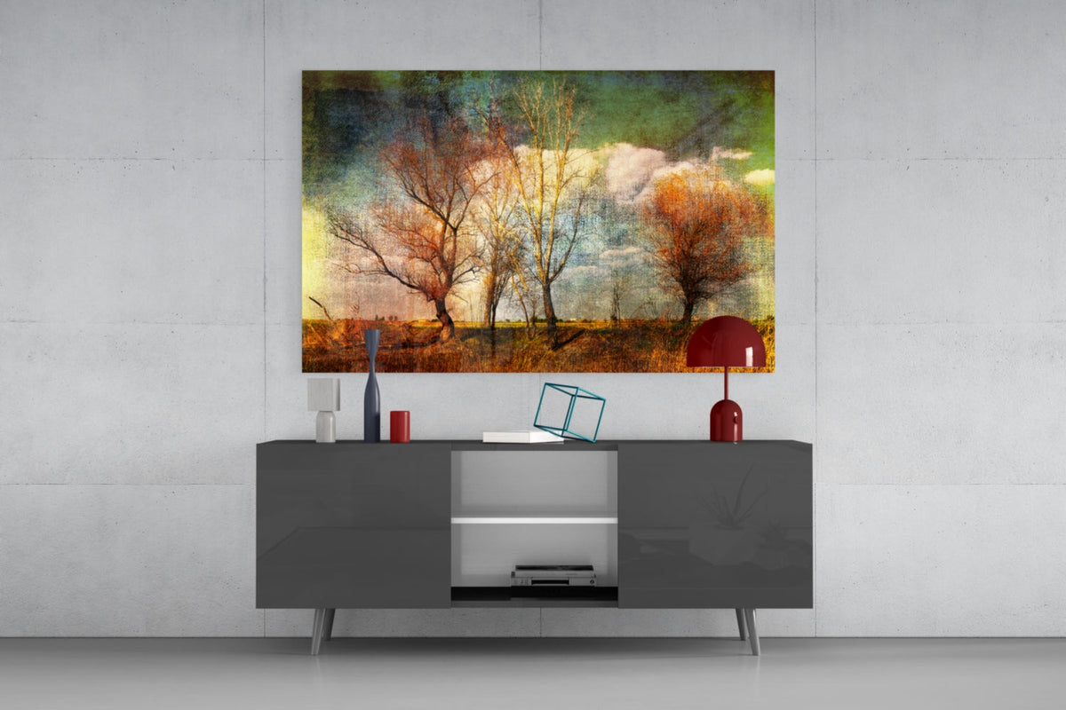 Autumn trees in a golden meadow glass wall art above a gray sideboard on a pale concrete wall