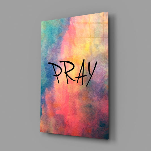 Pray watercolor word glass wall art angled against a soft gray backdrop