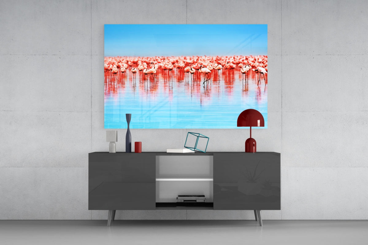 Pink flamingo flock glass wall art above a dark gray sideboard with a small red lamp