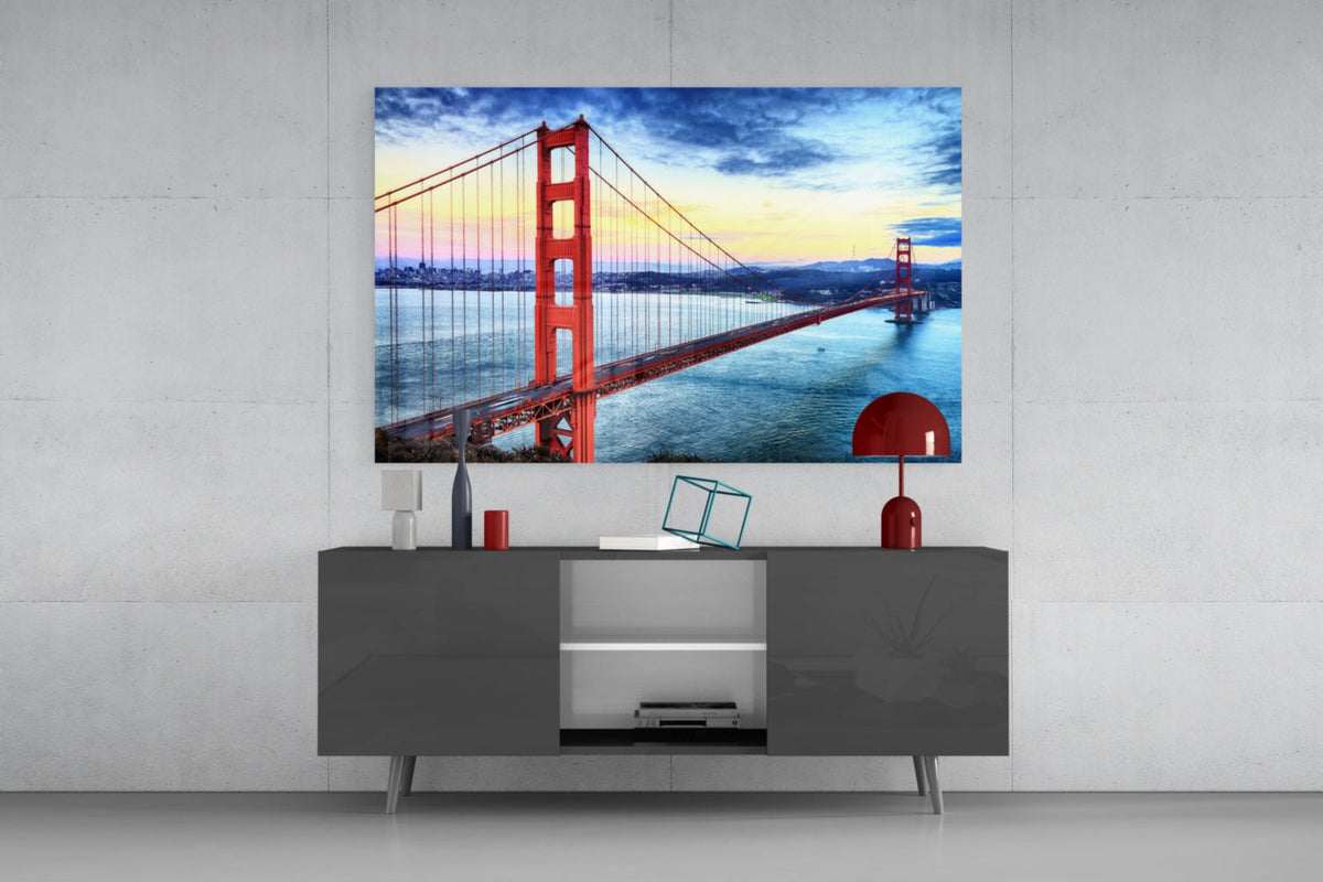 Golden Gate Bridge glass wall art above a gray sideboard with a red table lamp