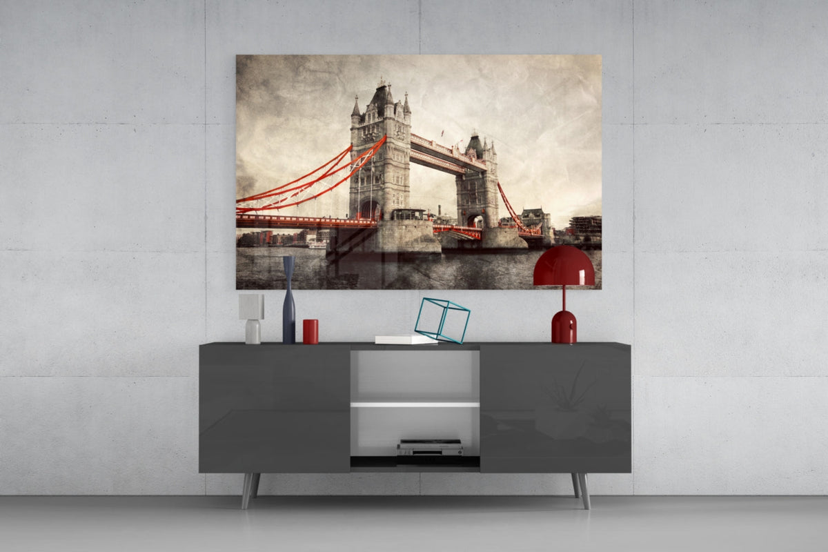 Tower Bridge glass wall art above a gray sideboard with a red table lamp