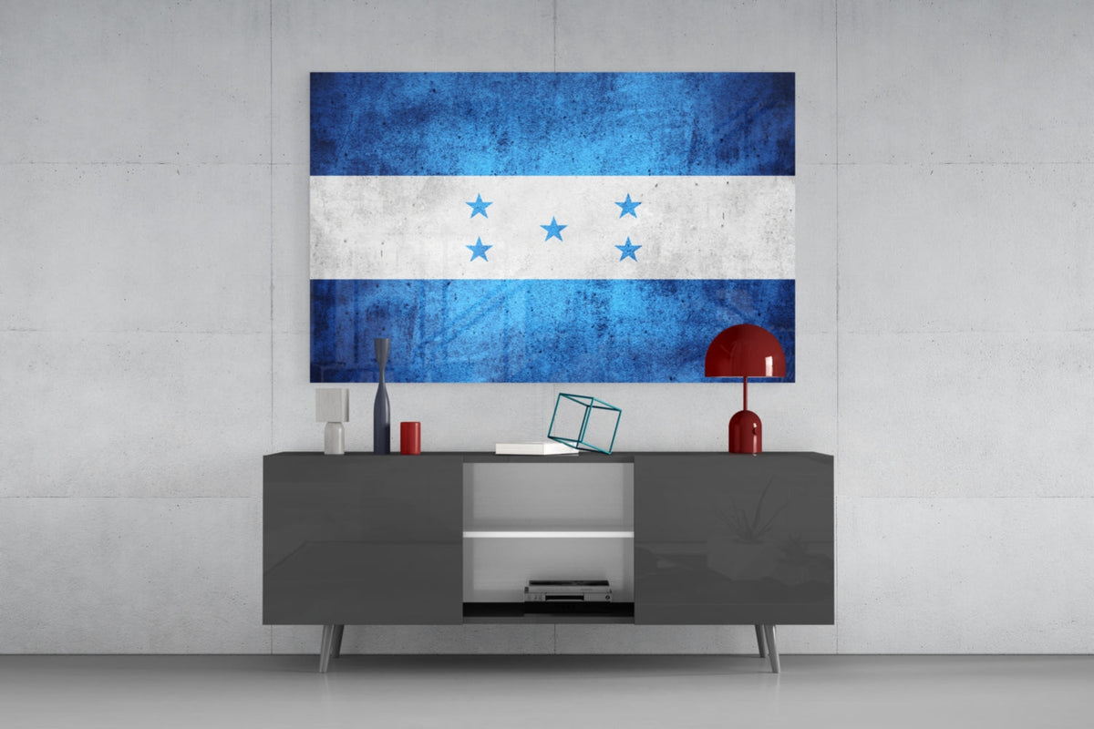 Weathered Honduras five star flag glass wall art above a dark gray media console with a red table lamp