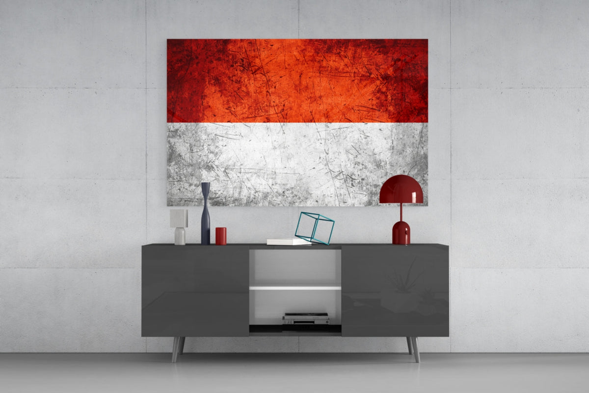 Weathered Indonesia red and white flag glass wall art above a dark gray media console with a red table lamp