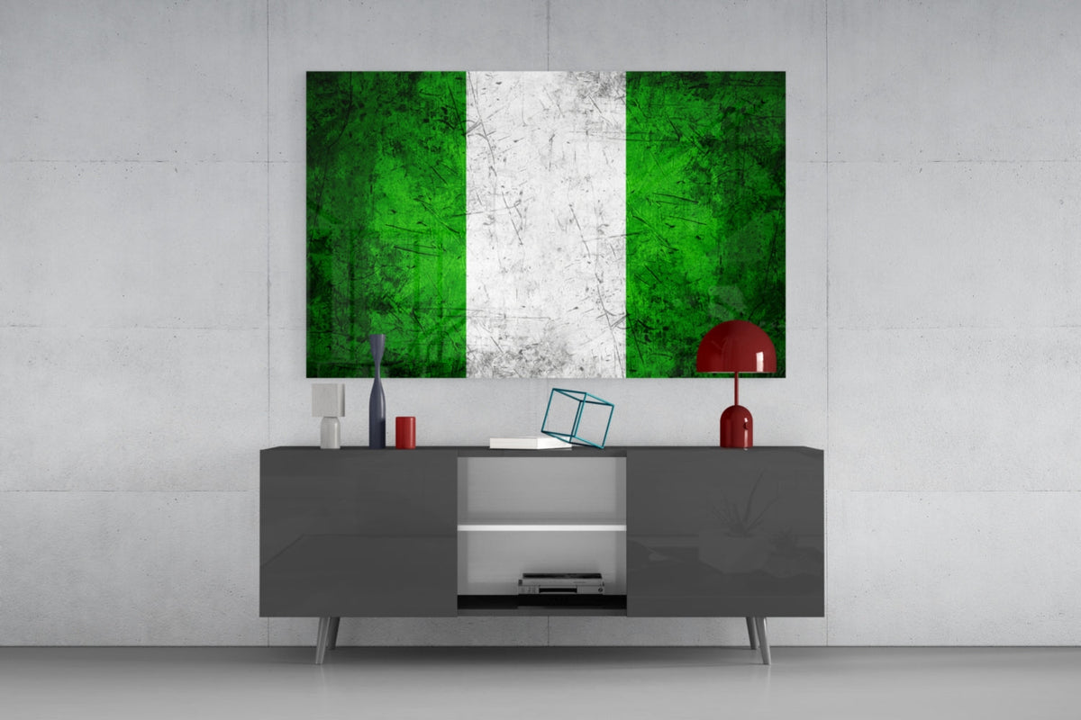 Weathered Nigeria flag glass wall art above a dark gray media console with a red table lamp