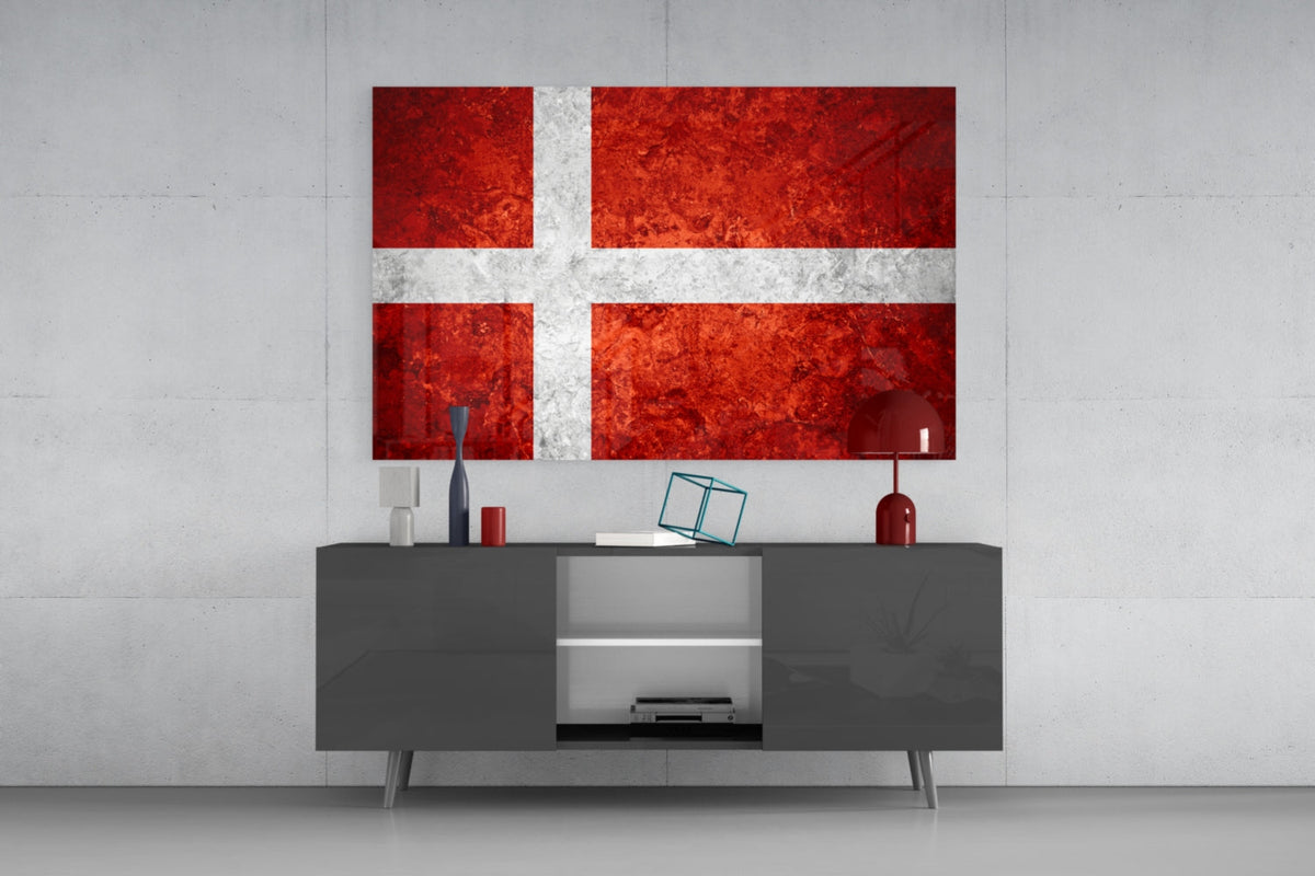 Mottled Denmark flag glass wall art above a dark gray media console with a red table lamp