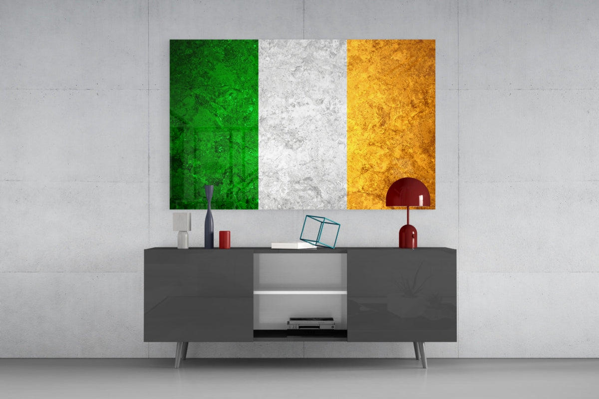 Weathered Ireland tricolor flag glass wall art above a dark gray media console with a red table lamp