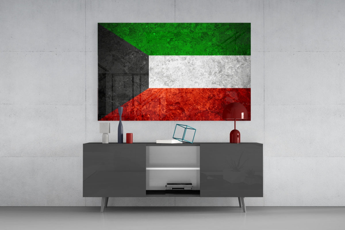 Weathered Kuwait flag glass wall art above a dark gray media console with a red table lamp