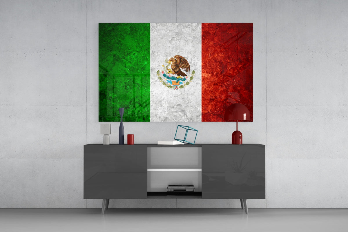 Weathered Mexico flag glass wall art above a dark gray media console with a red table lamp