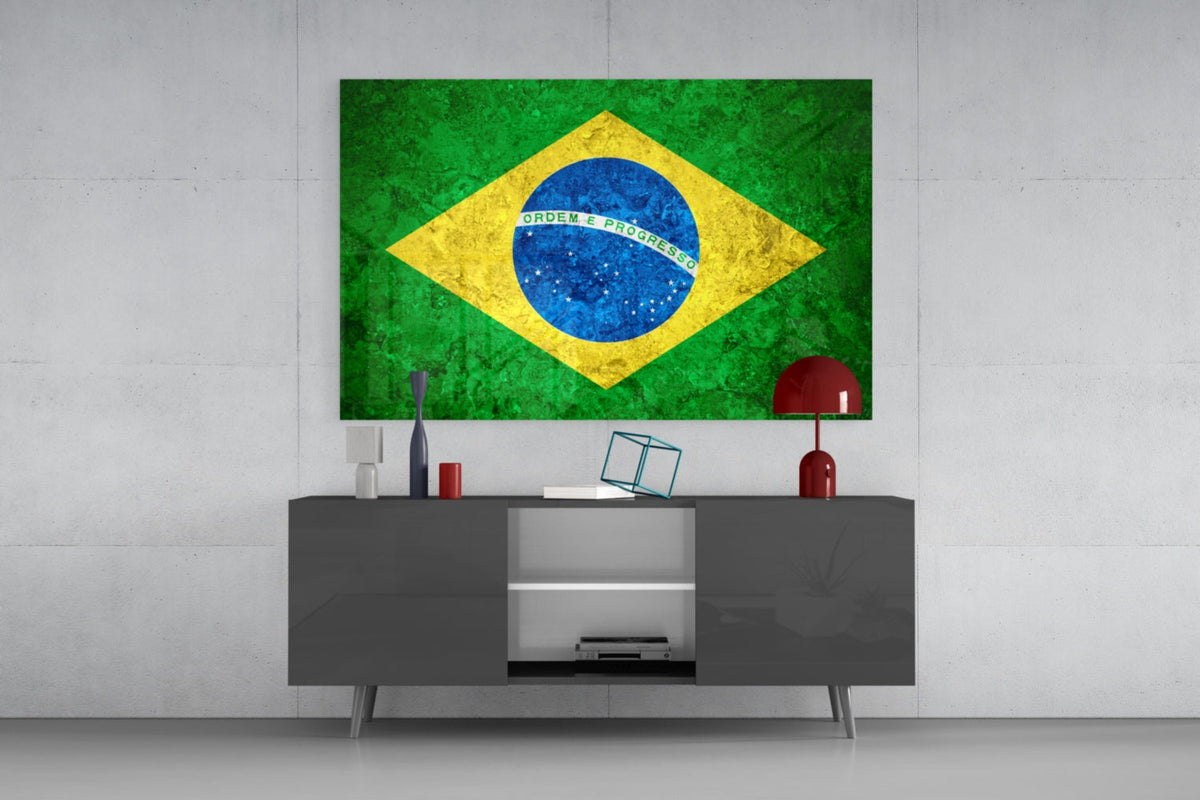 Stone texture Brazil flag glass wall art above a gray sideboard with a red lamp on a pale concrete wall