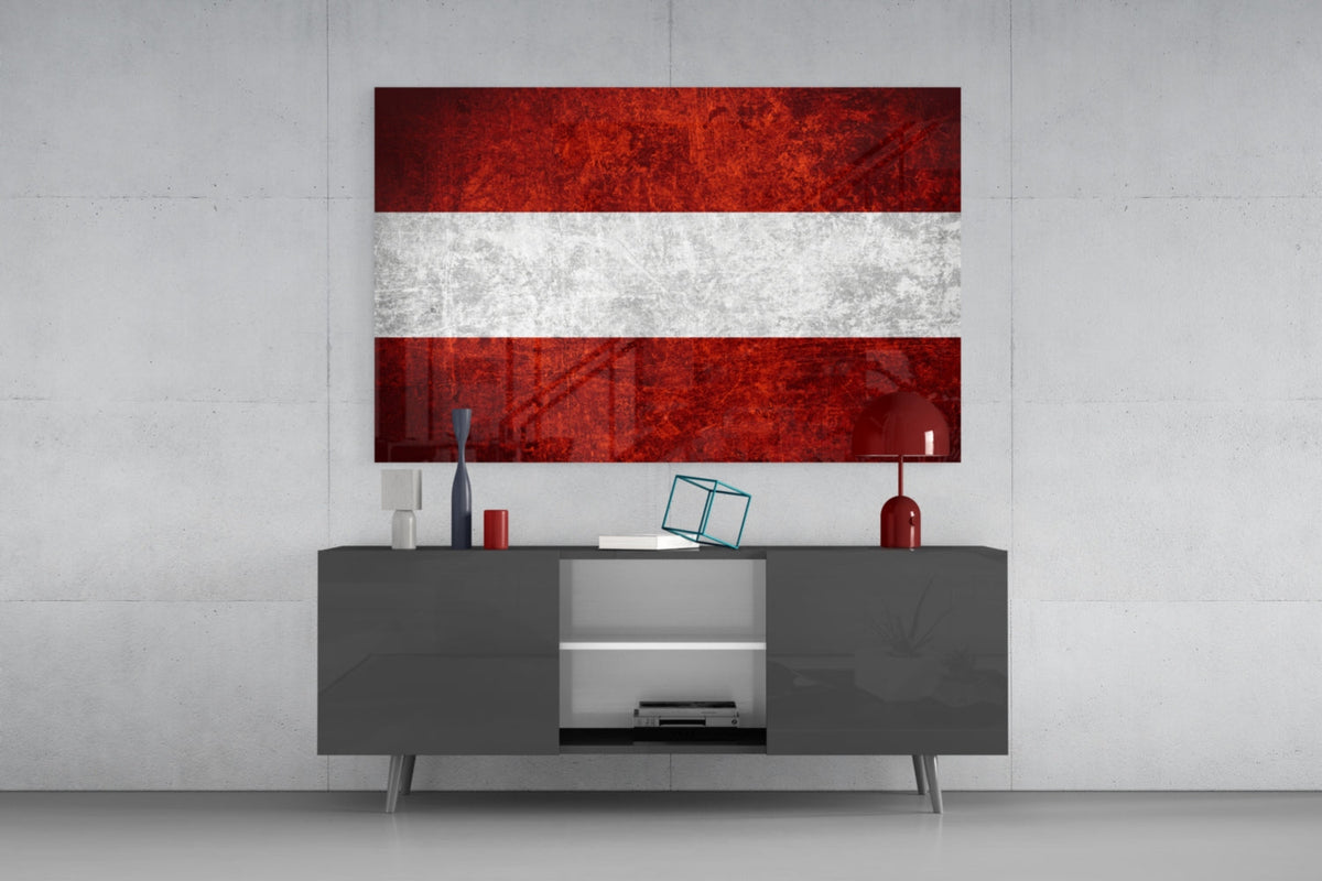 Weathered Austria flag glass wall art above a dark gray media console with a red table lamp