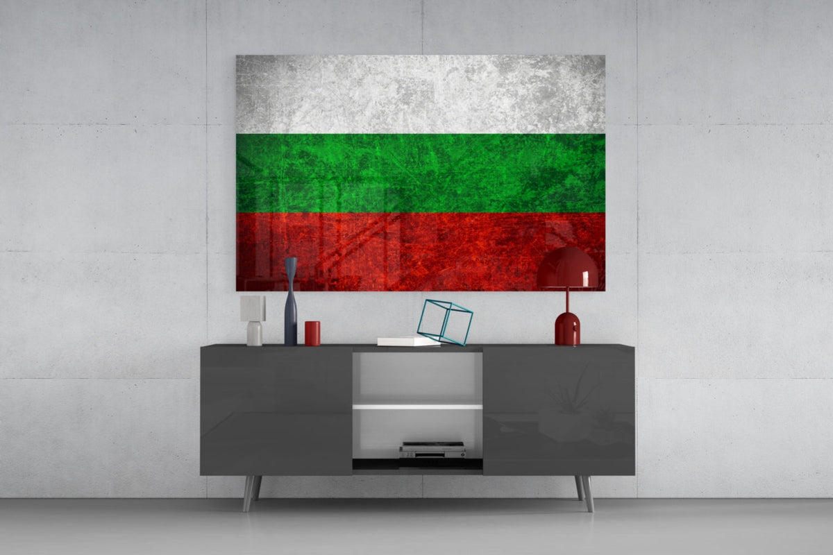 Weathered Bulgaria flag glass wall art above a dark gray media console with a red table lamp