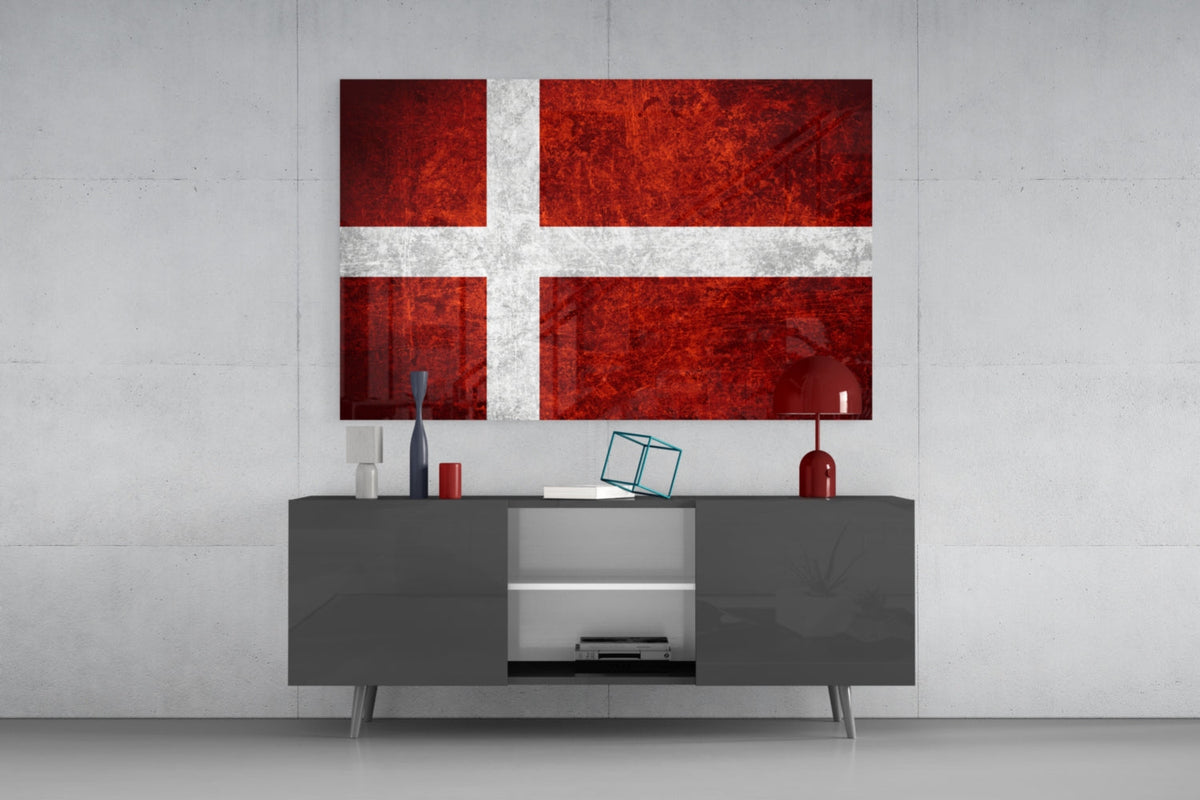Deep red weathered Denmark flag glass wall art above a dark gray media console with a red table lamp