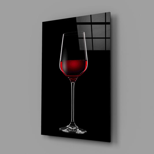 Red wine glass on black glass wall art on a gray wall with a soft window reflection