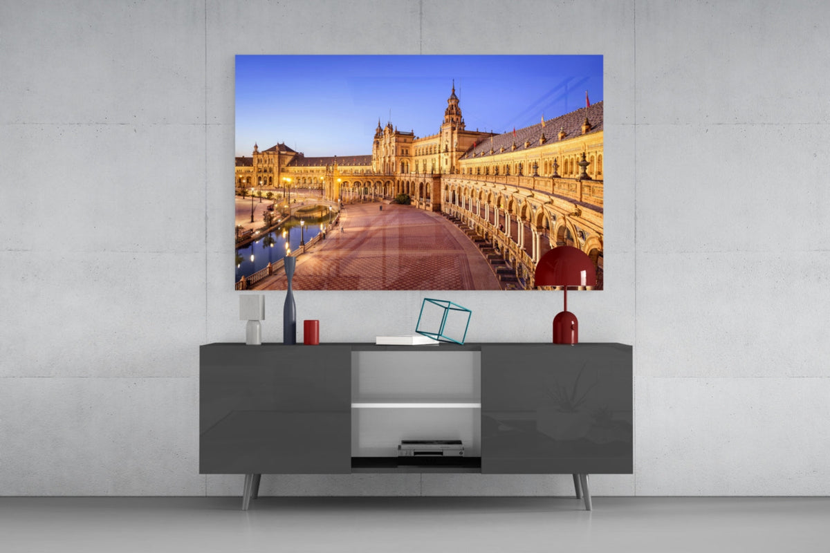 Plaza de Espana glass wall art above a gray sideboard with a red table lamp