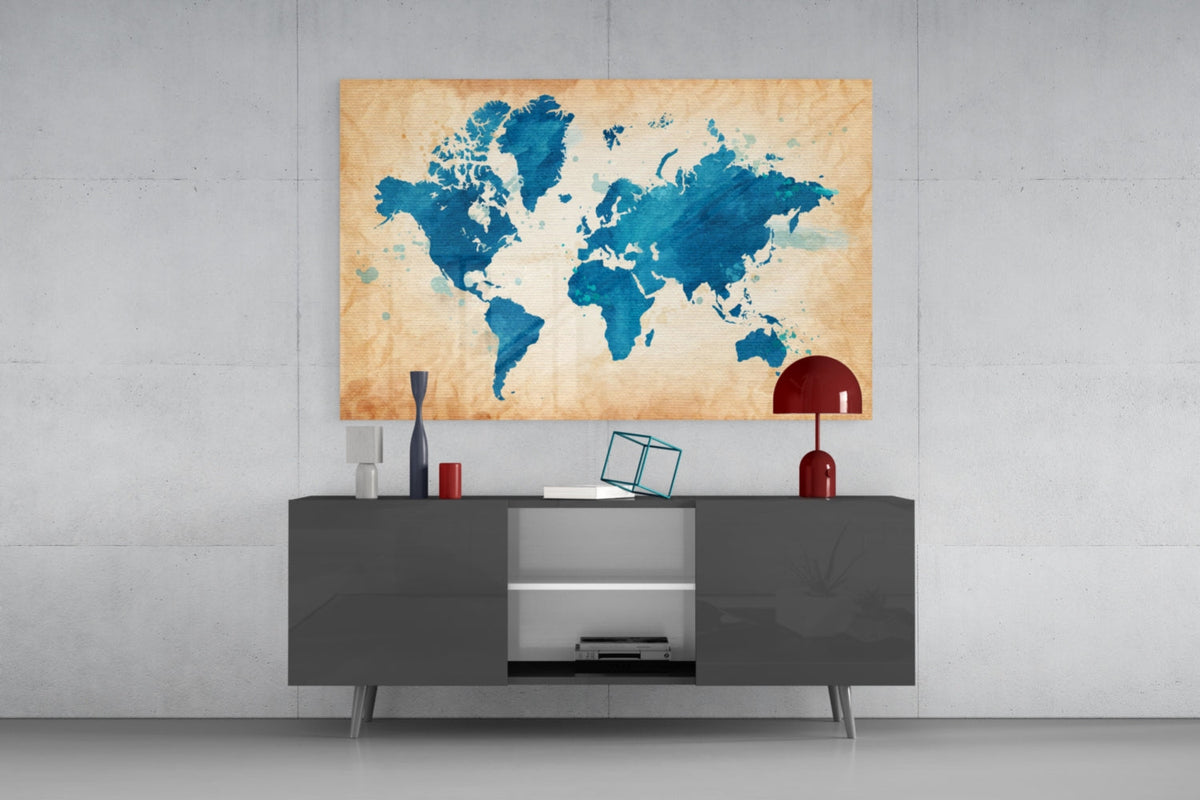 Blue watercolor world map glass wall art above a gray sideboard with a red table lamp