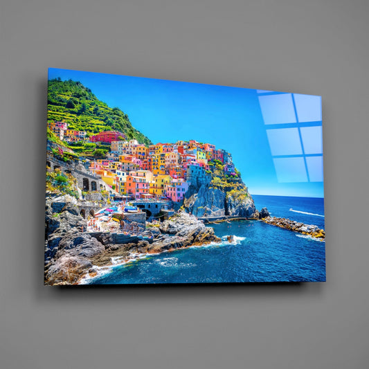 Manarola village glass wall art on a plain gray wall, angled to show the glossy surface