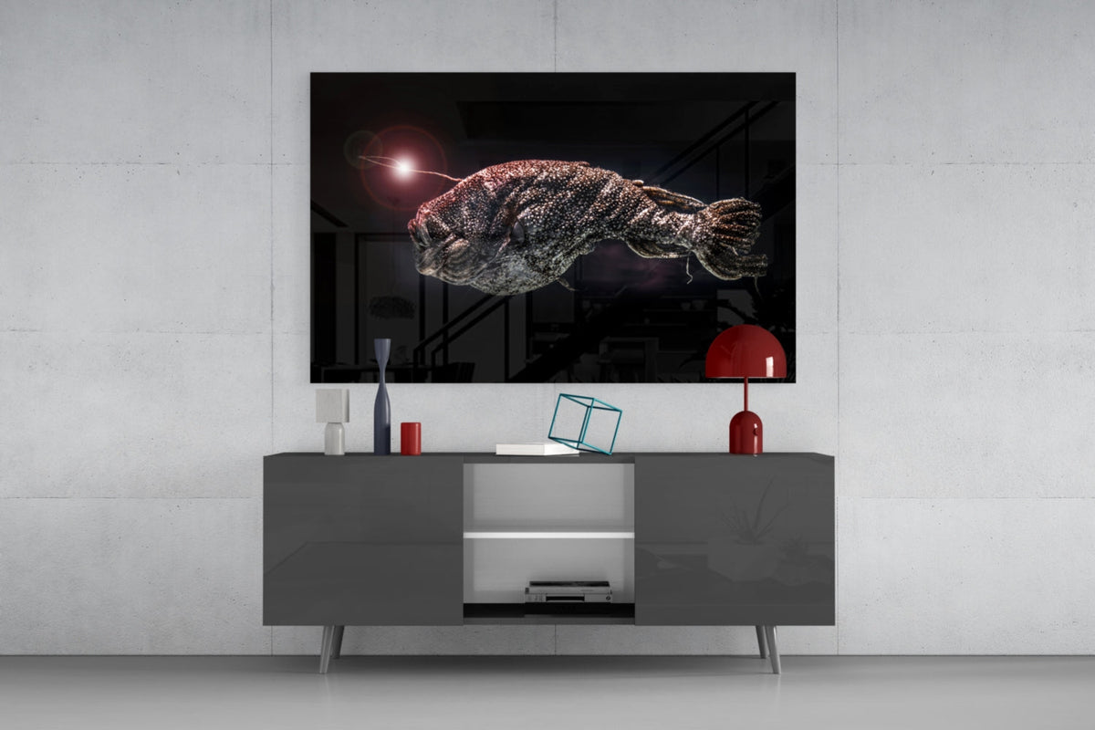 Deep sea anglerfish glass wall art above a dark gray sideboard with a small red lamp