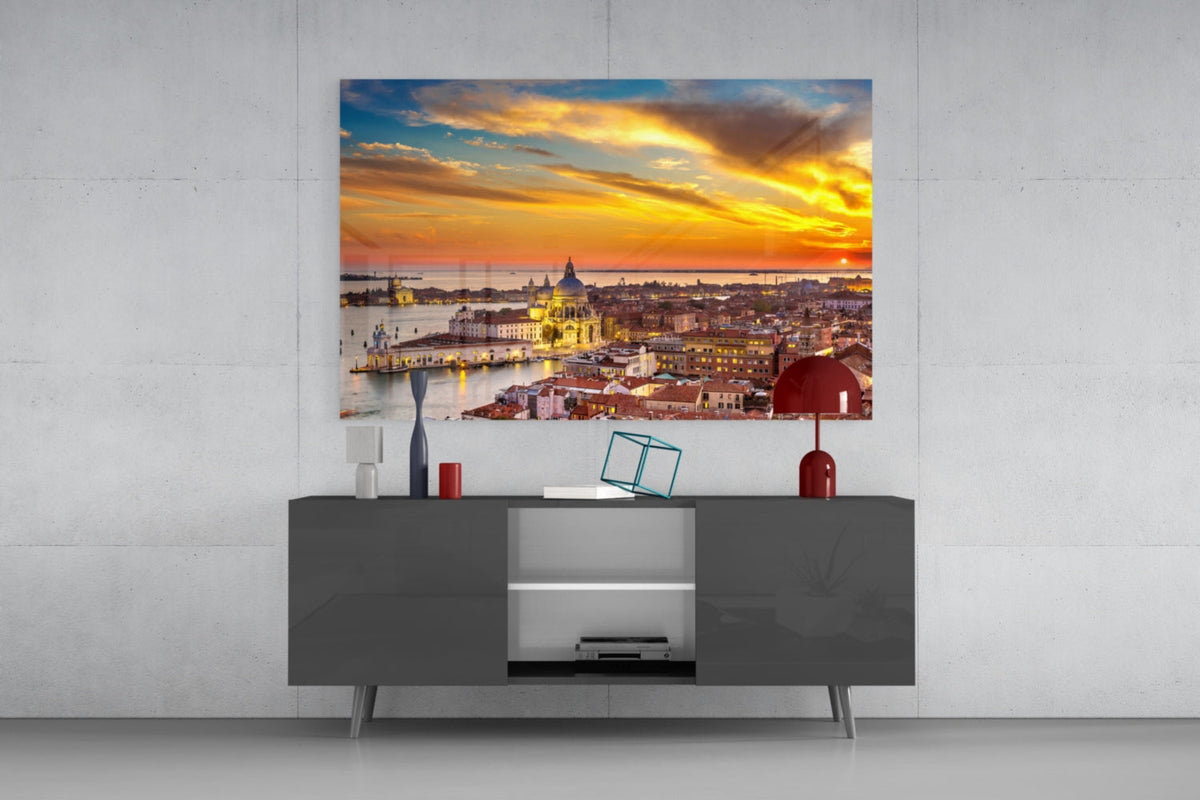 Venice rooftops glass wall art above a gray sideboard with a red table lamp